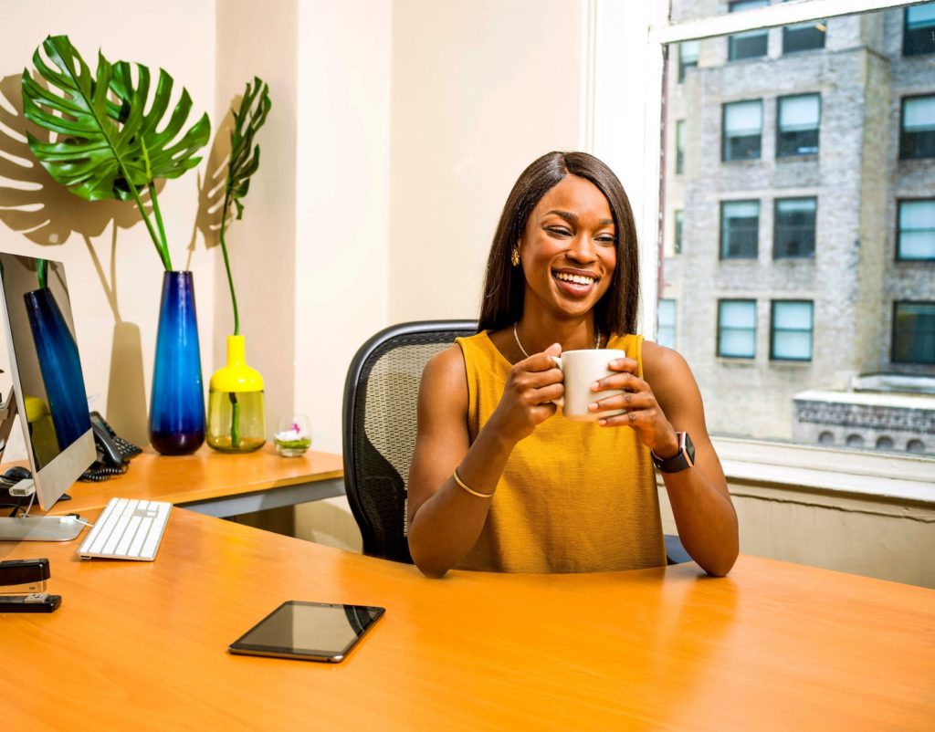 woman holding white ceramic mug at desk